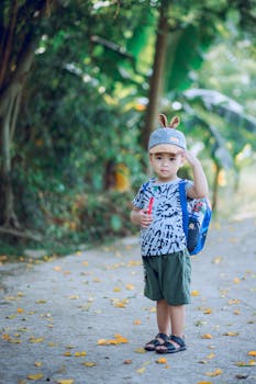 Adorable young boy with backpack enjoying a summer day outdoors, exuding joy and innocence.